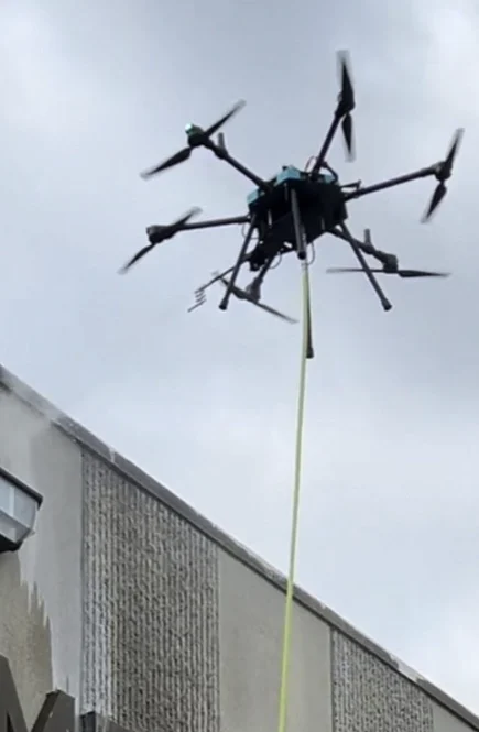 Cleaning drone operating beside a building exterior