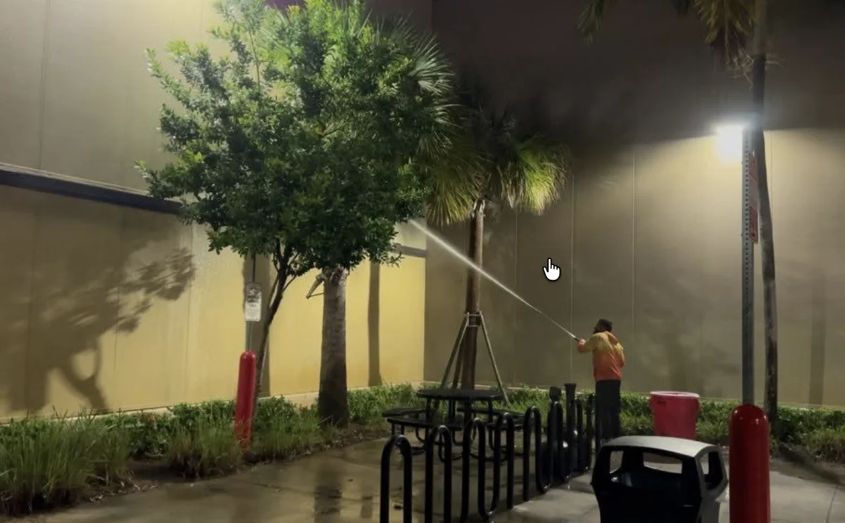 Technician softwashing a Costco building exterior in Miami at night