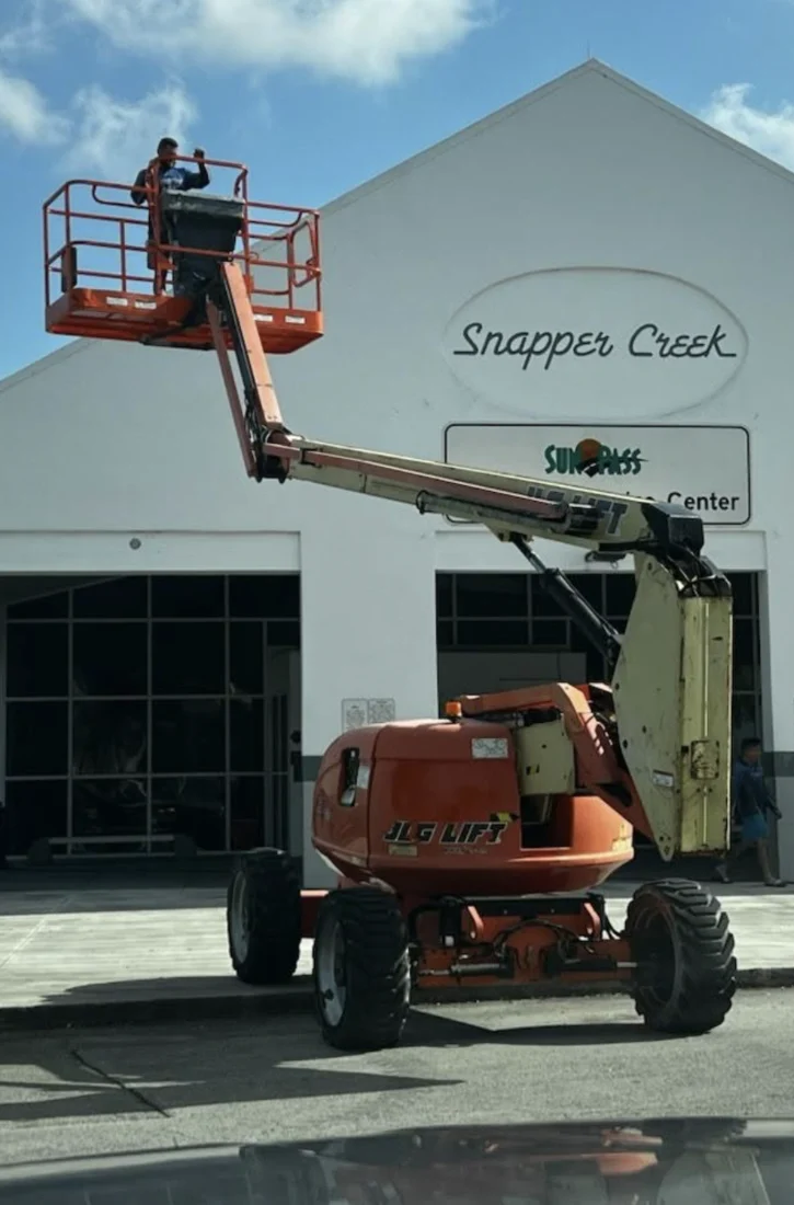 Pressure Kleen technician on a boom lift beside the Snapper Creek building during the FDOT project