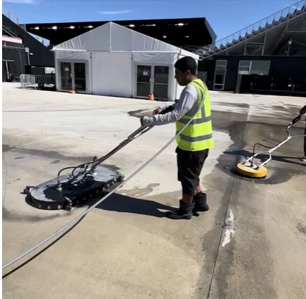 Technician cleaning a parking surface by the stadium