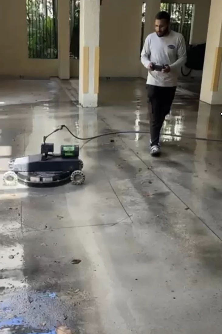Operator using a LavoBot robotic cleaner in a covered parking area