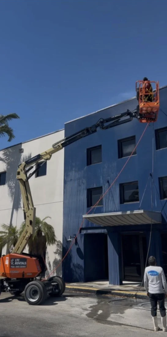Boom-lift access along a blue industrial building in Medley