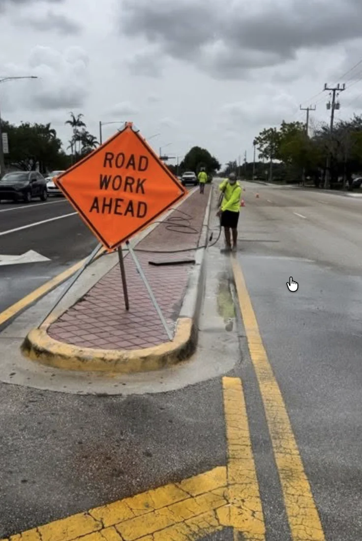 Crew washing a Tamarac road median beside a road-work warning sign