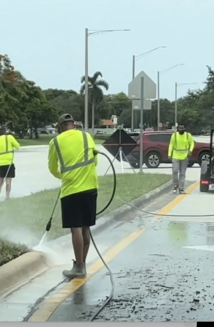 High-visibility crew cleaning a Tamarac median within a coned work area