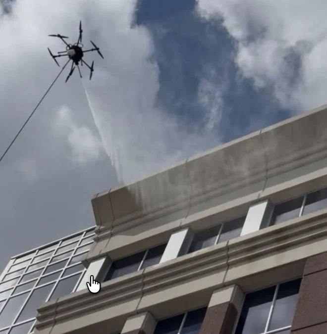 Cleaning drone washing the upper exterior of a University of Miami campus building