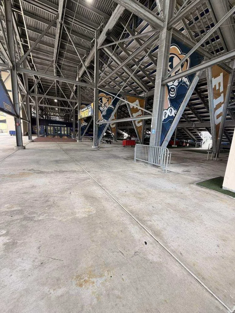 Concrete concourse beneath the FIU stadium stands with Panthers graphics and structural supports